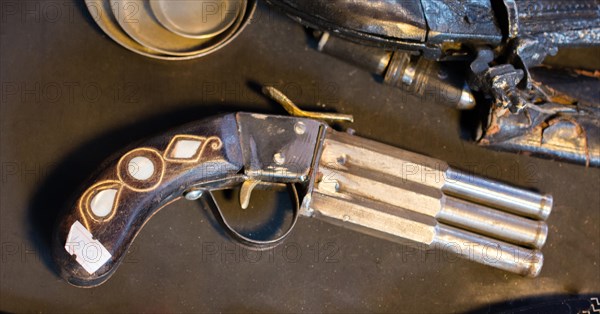 Antique stylistic revolve-like gun on a wooden background