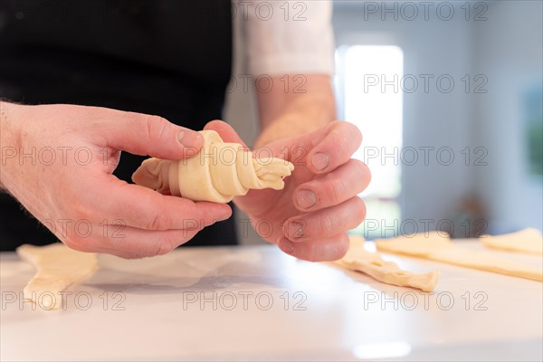 Hands of a man baking small croissants at home
