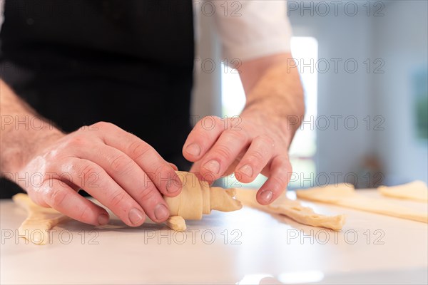 Hands of a man baking croissants
