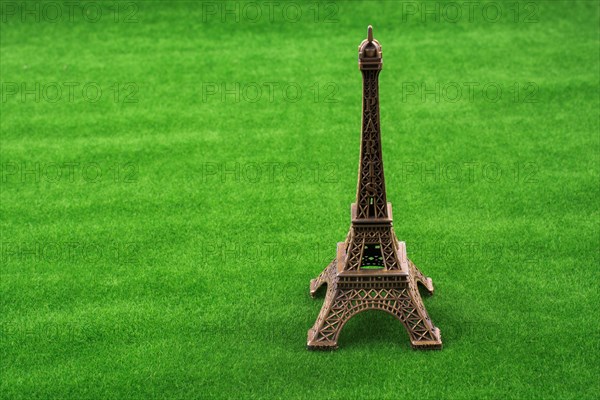 Little model Eiffel Tower on fake green grass field