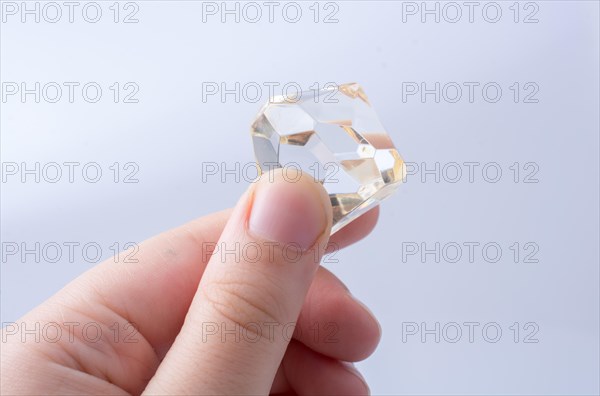 Hand holding a transparent diamond on a white background
