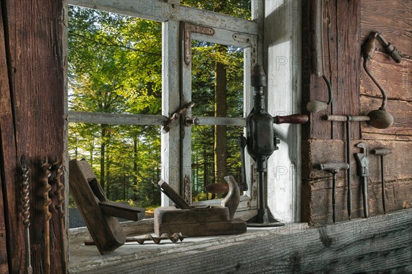 Rustic workshop with old tools and view out of the window into the forest
