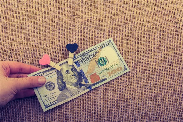American 100 dollar banknotes with a heart clip on a string