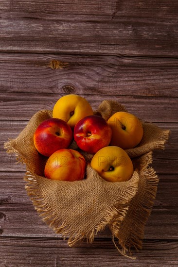 Group of fresh nectarines on a raffia cloth with a dark wood background