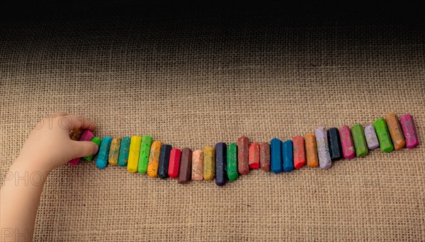 Toddlers hand putting crayons in line on canvas