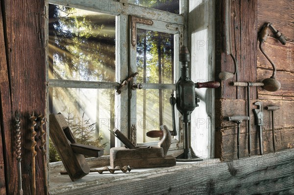 Rustic workshop with old tools and view out of the window into the forest