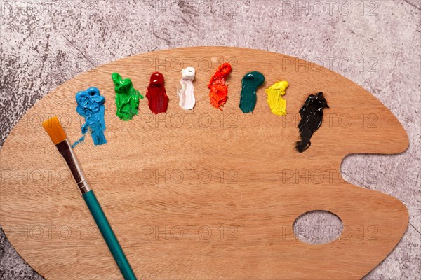 Top view of a palette with oil paints and brushes on a gray table