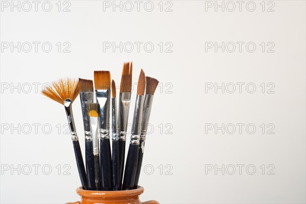 Earthenware jar with brushes isolated on a white background