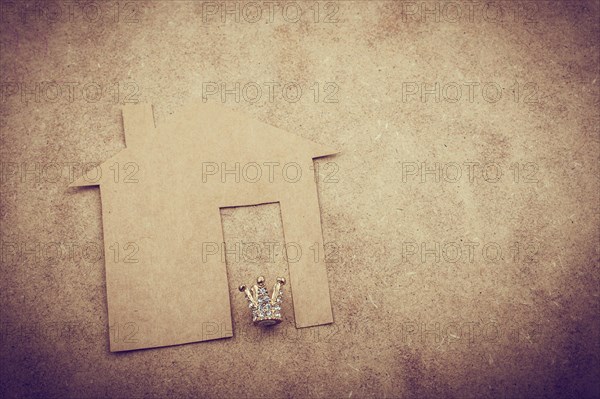 Litle model crown and paper house on a brown background