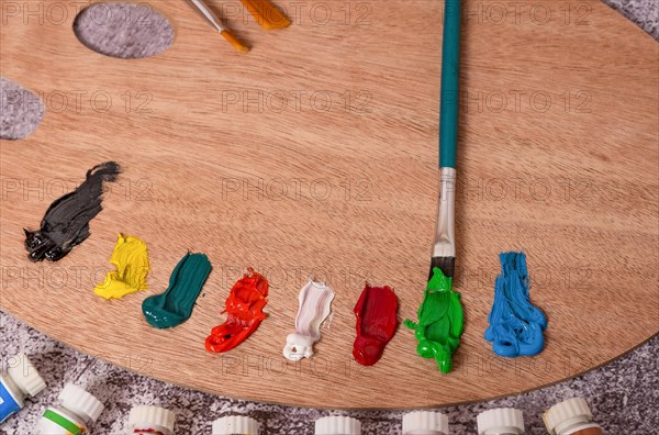 Top view of a palette with oil paints and brushes on a gray table