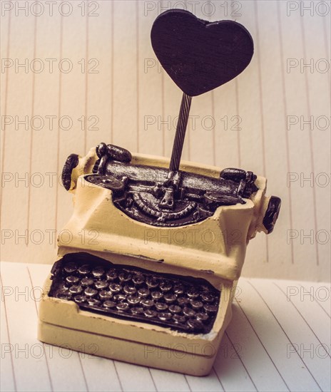 Retro syled tiny typewriter model on a paper background