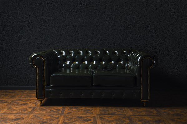 Glossy green leather couch next to black wall