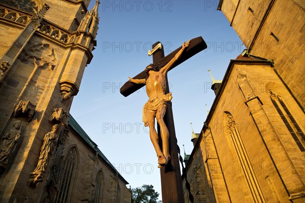 Jesus Christ on the cross between Erfurt Cathedral and Severi Church in early morning light