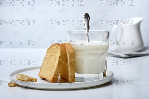 Rusk and glass of milk with spoon