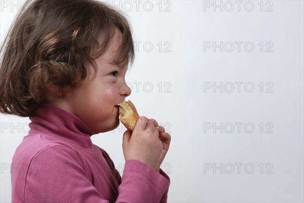 A young girl eating a bun
