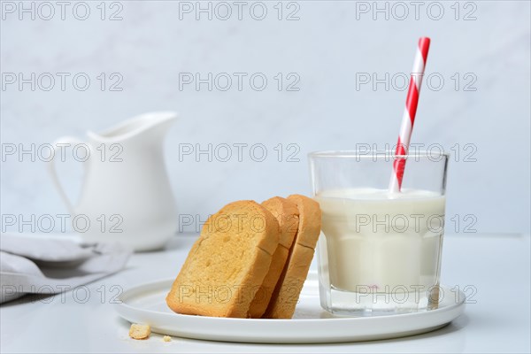 Rusk and glass of milk with drinking straw