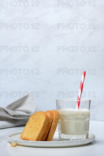 Rusk and glass of milk with drinking straw