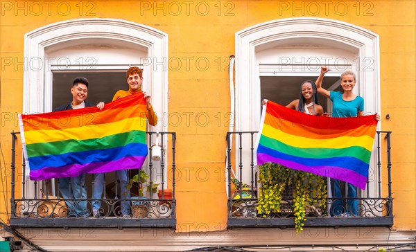 Couples of gay boys and lesbian girls with the lgtb flag on the balconies at a house party, greeting friends, LGBT pride