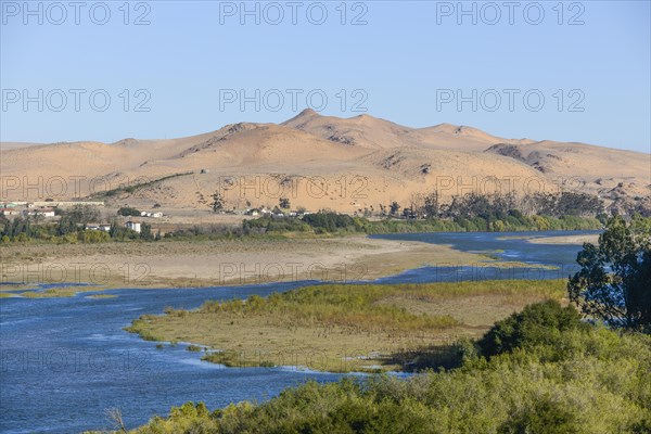 Orange River, also known as the Orange River, on the border between Namibia and South Africa, sand dunes behind, Oranjemund, Sperrgebiet National Park, also known as Tsau ÇKhaeb National Park, Namibi...