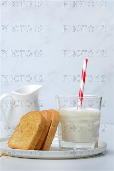 Rusk and glass of milk with drinking straw