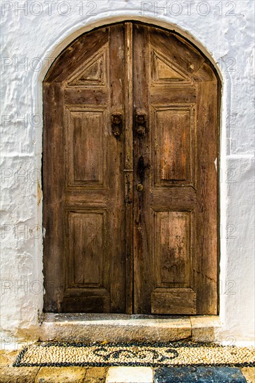 Old wooden doors with pebble mosaics on the floor, winding streets with white houses, Lindos, Rhodes, Greece, Europe