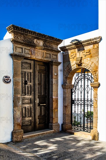Old wooden doors with pebble mosaics on the floor, winding streets with white houses, Lindos, Rhodes, Greece, Europe