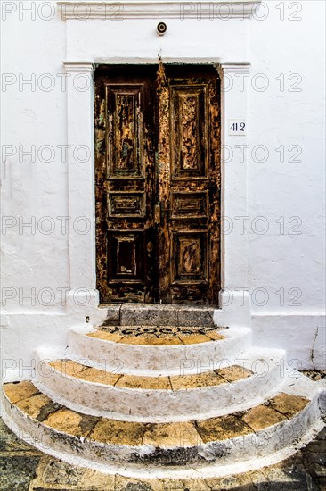 Old wooden doors with pebble mosaics on the floor, winding streets with white houses, Lindos, Rhodes, Greece, Europe