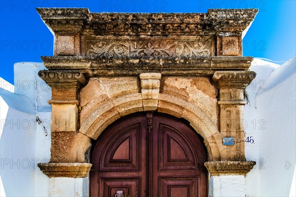 Old wooden doors with pebble mosaics on the floor, winding streets with white houses, Lindos, Rhodes, Greece, Europe