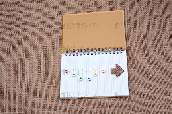 Love cubes and paper arrow on a notebook on canvas