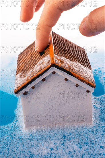 Little model house and a painting brush in foamy water