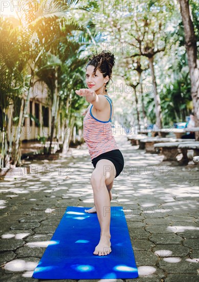 Young woman doing yoga virabhadrasana II outdoors. Girl practicing yoga Warrior II pose outdoors. Latin woman doing yoga warrior pose outdoors