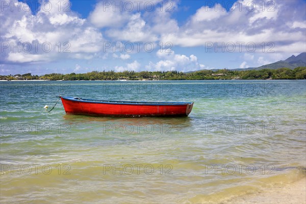 Red fishing boat lies tied up near the beach