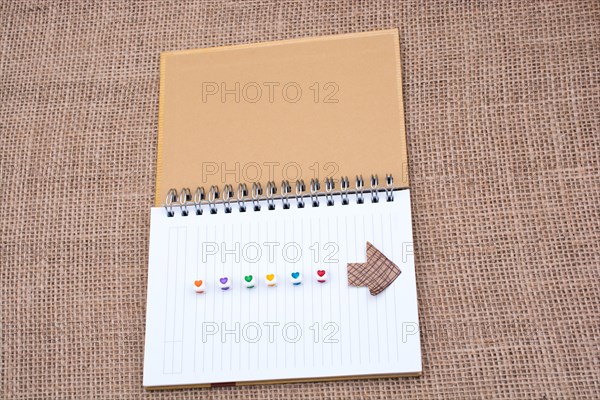 Love cubes and paper arrow on a notebook on canvas