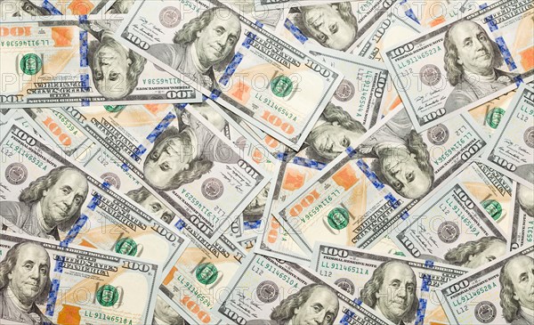 One hundred dollar bills laying on flat surface