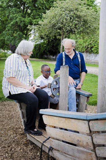 Temporary grandparents. Elderly couple volunteer to look after a boy from Africa for a few hours a week.
