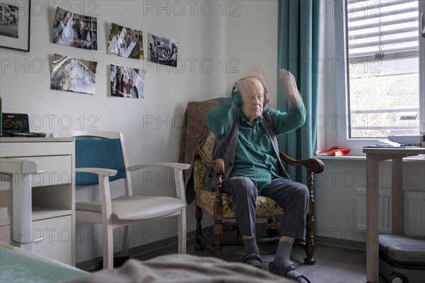 Old man in nursing home conducts to music