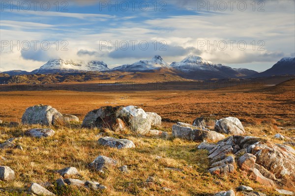 Striking boulders in the wintry Scottish Highlands with the snow-capped mountains of Suilven and Stack Polly in the background