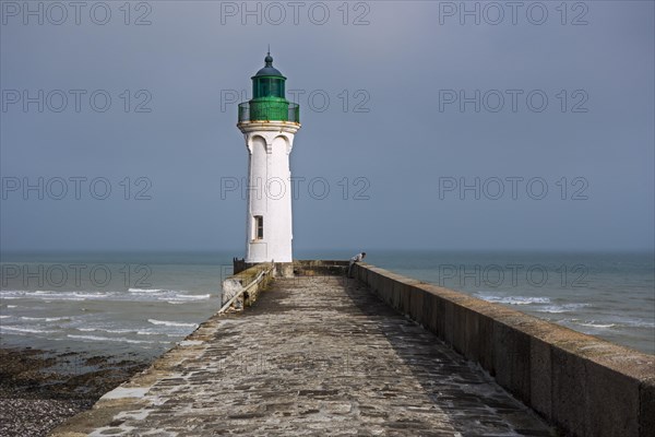 Lighthouse and lonely man looking at sea from pier in the harbour at Saint-Valery-en-Caux