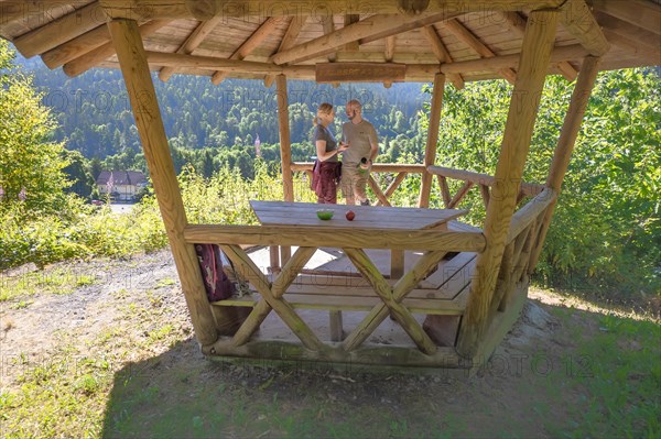 Hiking couple taking a break in wooden pavilion on the hiking trail Sprollenhaeuser Hut