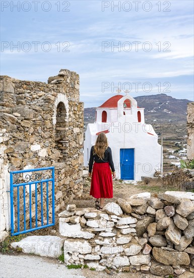 Young woman with red skirt at the entrance gate with ruined wall