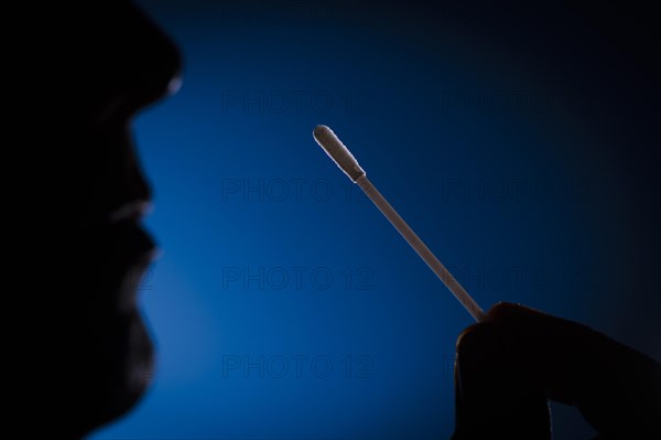 A man holds cotton swabs of a Sars-COV-2 Rapid Antigen Test to his nose. Berlin