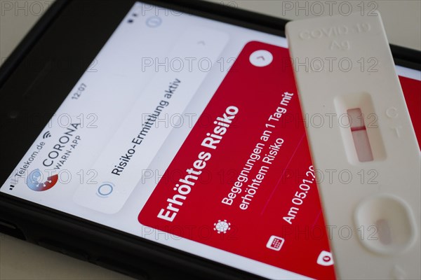 A negative rapid test is on a smartphone on which the Corona Warn app displays the words Increased Risk. Berlin