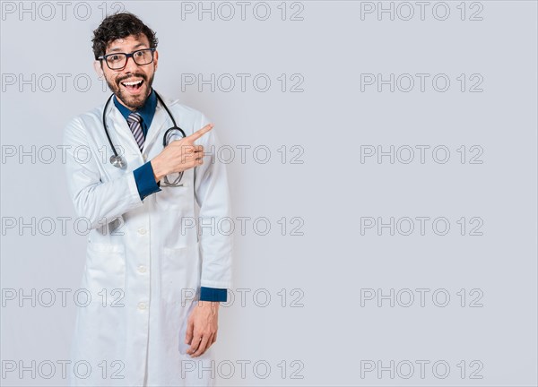 Young doctor pointing a promotion with finger. Happy doctor pointing at advertising space isolated. Happy doctor pointing right with finger