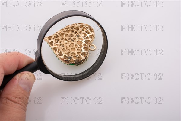 Heart shaped gold color metal under magnifying glass
