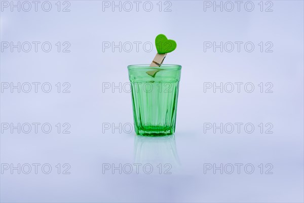 Drinking glass of gtreen color and a clothespin with a heart