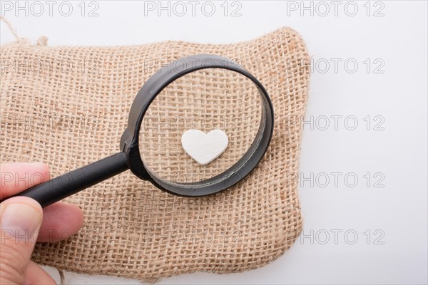 Heart shaped metal object behind magnifying glass