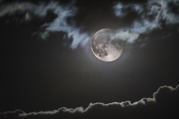 Rising full moon illuminates jagged cloud edge
