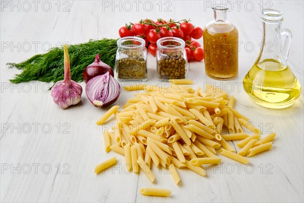 Uncooked pasta farfalline scattered on the table surrounded with ingredients