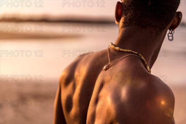 Back of muscular black ethnic man on summer vacation by the sea feeling free