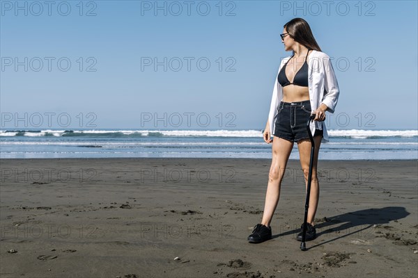 Young woman with cane looking at the sea. Cancer survivor
